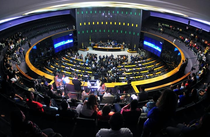 Vista ampla do plenário da Câmara dos Deputados, com parlamentares reunidos próximo à mesa principal e público nas galerias.